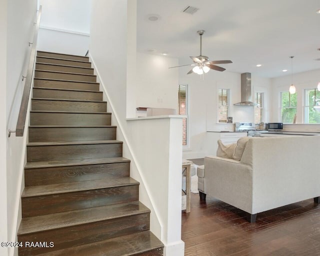 stairway with ceiling fan and dark hardwood / wood-style flooring