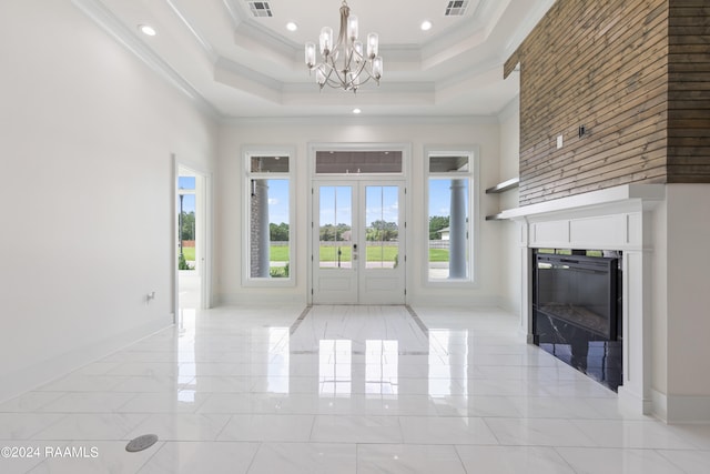 entryway featuring an inviting chandelier, a raised ceiling, crown molding, and a high ceiling