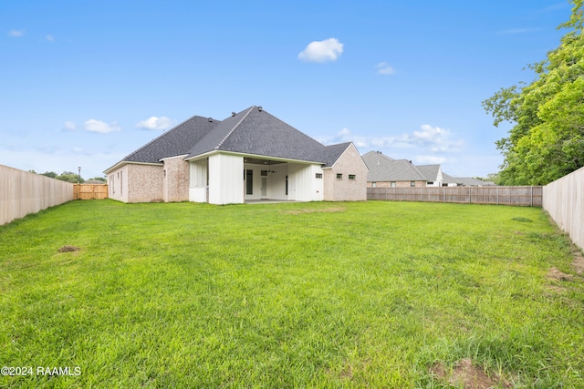 rear view of property featuring a yard and a patio area