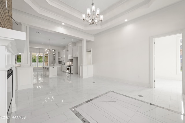 foyer featuring decorative columns, ornamental molding, a tray ceiling, and a chandelier