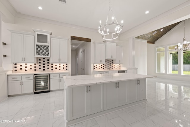 kitchen featuring backsplash, marble finish floor, beverage cooler, and a chandelier