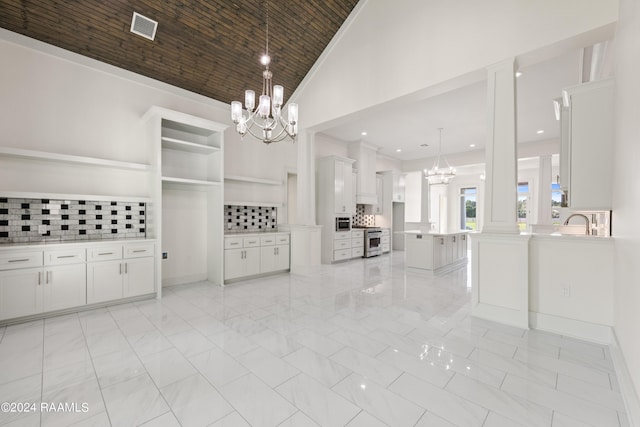 unfurnished dining area featuring marble finish floor, visible vents, ornamental molding, a sink, and a notable chandelier