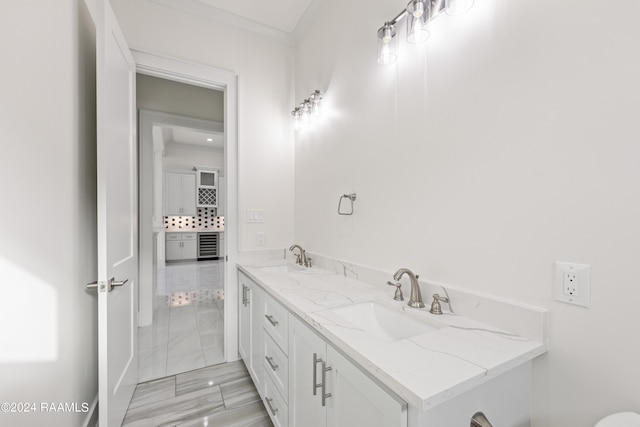 bathroom with double vanity, beverage cooler, marble finish floor, and a sink