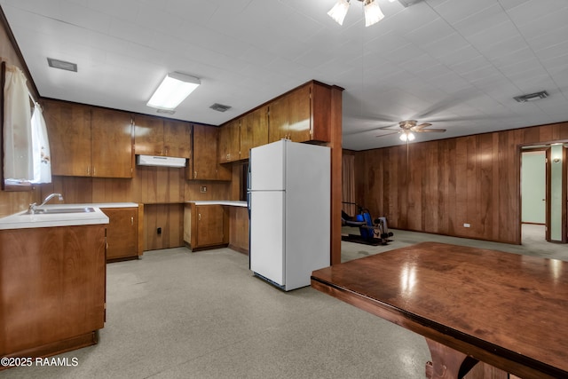 617 Cemetery Rd, Saint Martinville, LA 70582 - kitchen featuring freestanding refrigerator, ceiling fan, wood walls, under cabinet range hood, and brown cabinetry