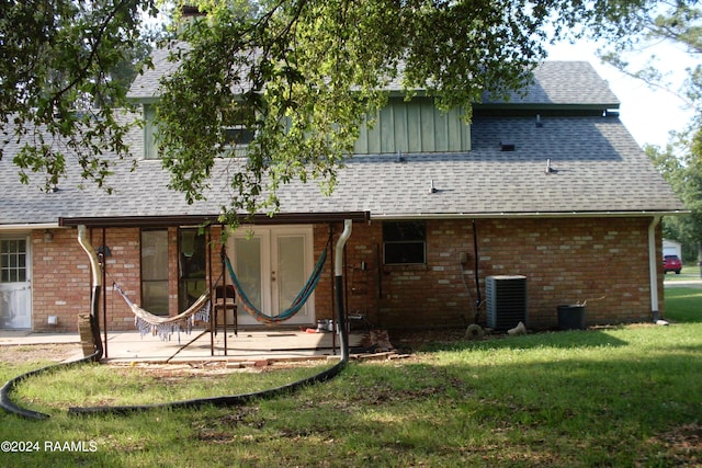 rear view of property featuring central AC unit and a lawn