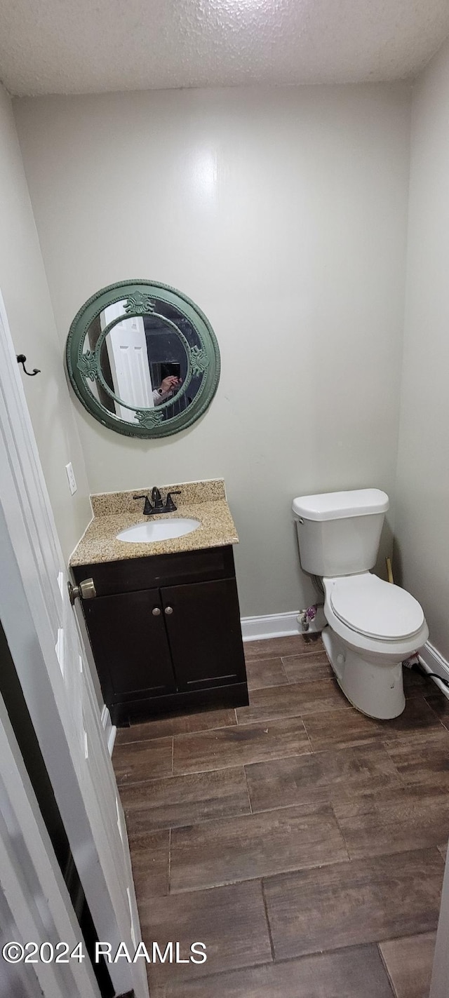 bathroom with a textured ceiling, hardwood / wood-style flooring, toilet, and vanity