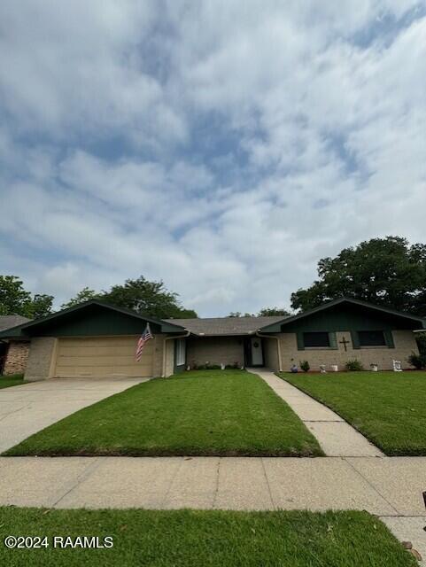 ranch-style home featuring a garage and a front lawn