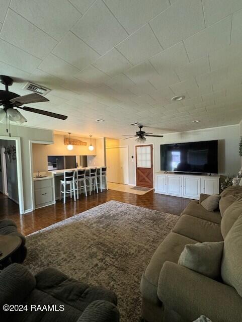 living room with ceiling fan and dark hardwood / wood-style flooring