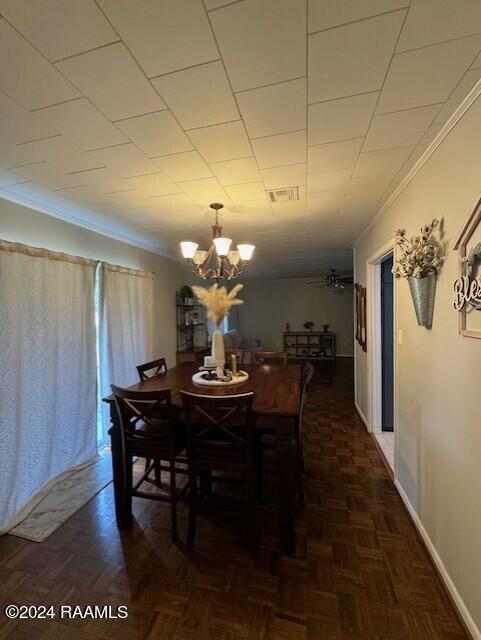 dining area with crown molding, dark parquet floors, and ceiling fan with notable chandelier