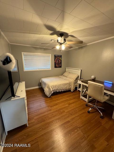 bedroom featuring dark hardwood / wood-style floors, ceiling fan, and crown molding