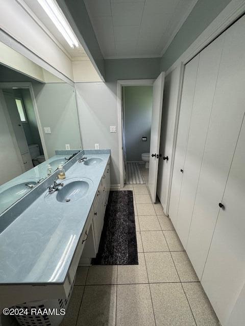 bathroom with tile patterned floors, vanity, toilet, and crown molding