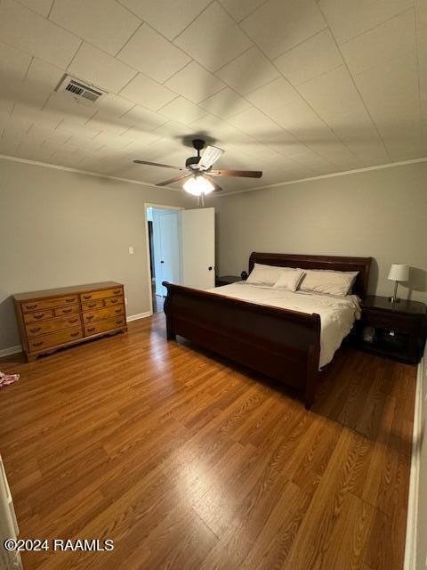 unfurnished bedroom featuring ceiling fan, crown molding, and wood-type flooring