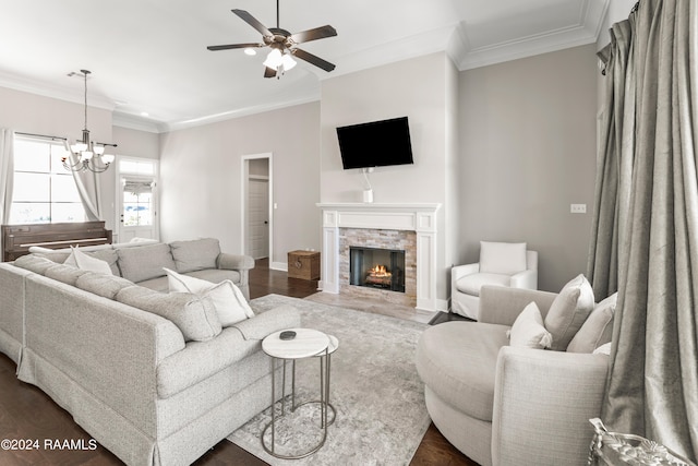 living room with ceiling fan with notable chandelier, crown molding, a fireplace, and dark hardwood / wood-style floors