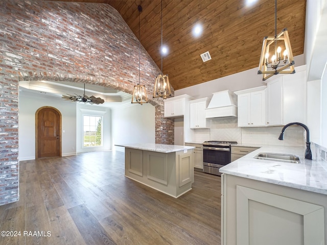 kitchen featuring custom range hood, high vaulted ceiling, stainless steel range oven, and sink