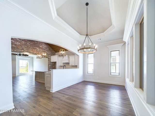 unfurnished dining area with a raised ceiling, ceiling fan, dark hardwood / wood-style flooring, and crown molding