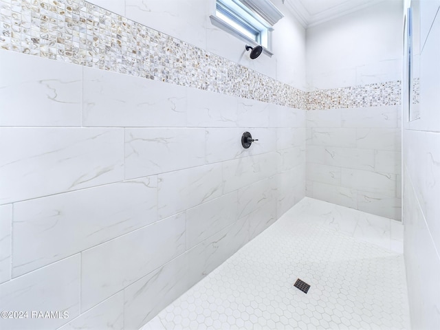 bathroom featuring a tile shower and crown molding