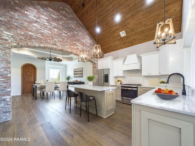 kitchen featuring a center island, high vaulted ceiling, custom exhaust hood, and appliances with stainless steel finishes