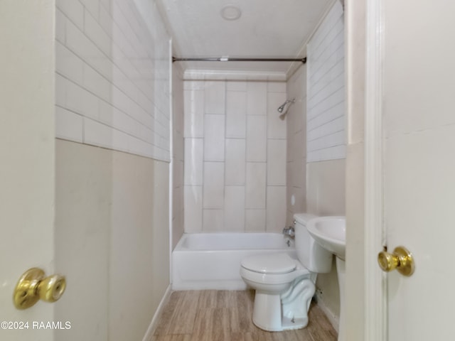 bathroom featuring hardwood / wood-style flooring, toilet, and tiled shower / bath combo