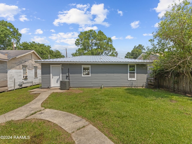 back of property featuring central AC and a lawn