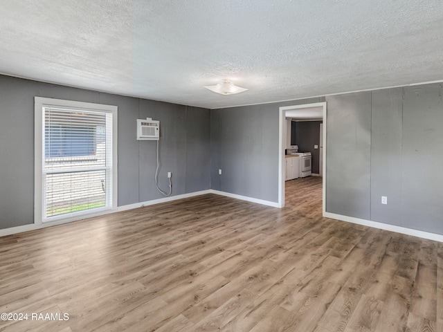 spare room with hardwood / wood-style floors, a textured ceiling, and a wall mounted air conditioner