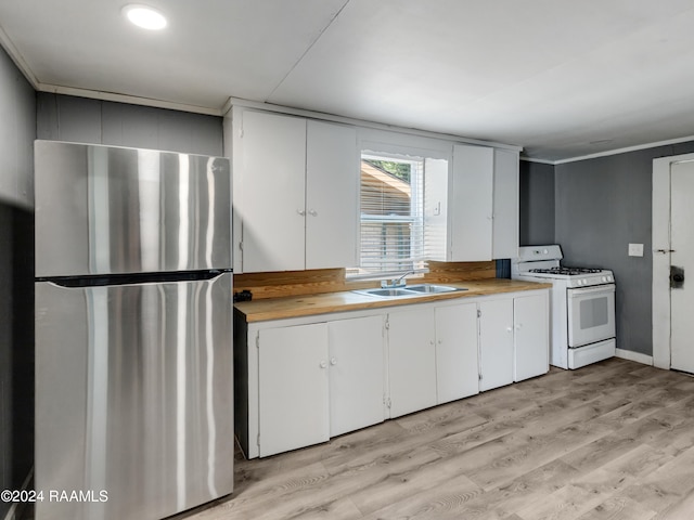 kitchen featuring white gas stove, sink, stainless steel fridge, and white cabinetry