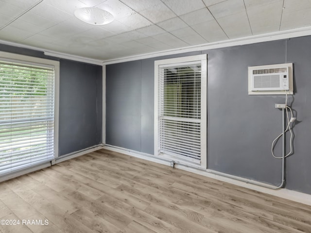 spare room featuring crown molding, a wall unit AC, and light wood-type flooring