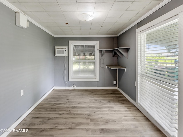 empty room with ornamental molding, light wood-type flooring, and a wall mounted air conditioner