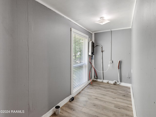 laundry area with water heater, ornamental molding, and light hardwood / wood-style flooring