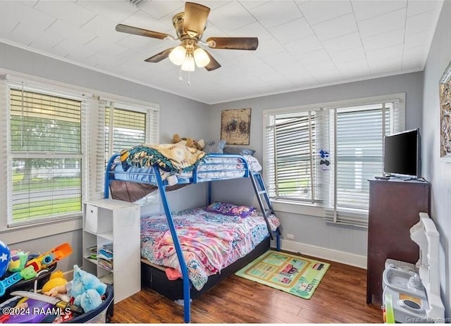 bedroom with ceiling fan, ornamental molding, and dark wood-type flooring