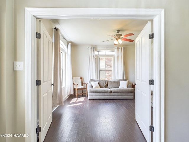 unfurnished living room featuring ceiling fan and dark wood-type flooring