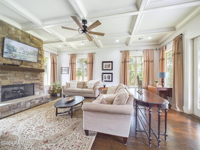 living room with coffered ceiling, ceiling fan, beam ceiling, dark hardwood / wood-style floors, and a stone fireplace