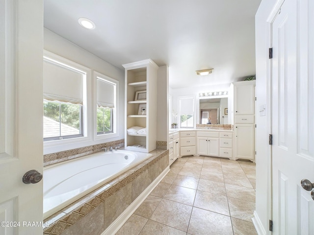 bathroom with tile patterned flooring, vanity, and a relaxing tiled tub