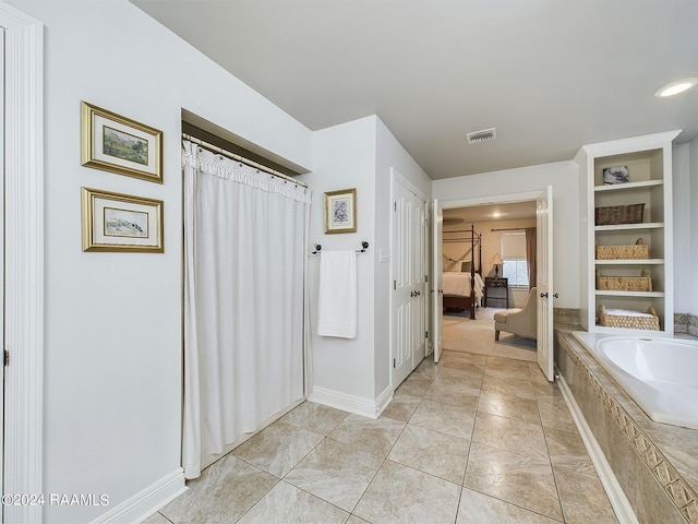 bathroom featuring tile patterned flooring and a relaxing tiled tub