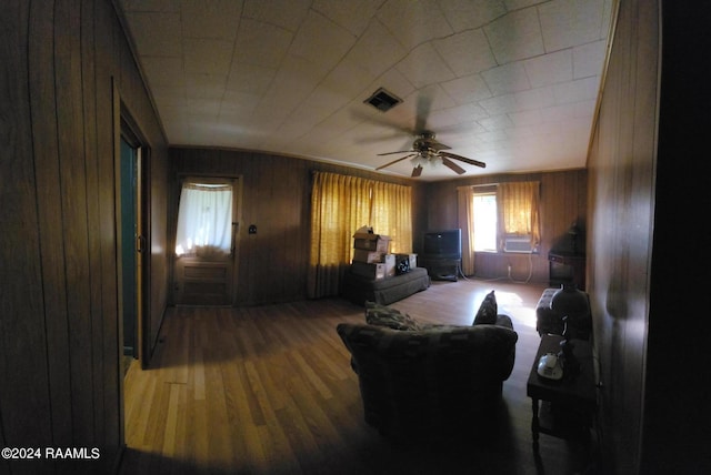 living room with wooden walls, ceiling fan, and hardwood / wood-style flooring