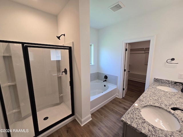 bathroom with plus walk in shower, hardwood / wood-style flooring, and vanity