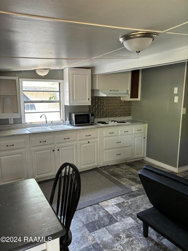 kitchen featuring decorative backsplash, white cabinets, tile patterned floors, and white electric cooktop