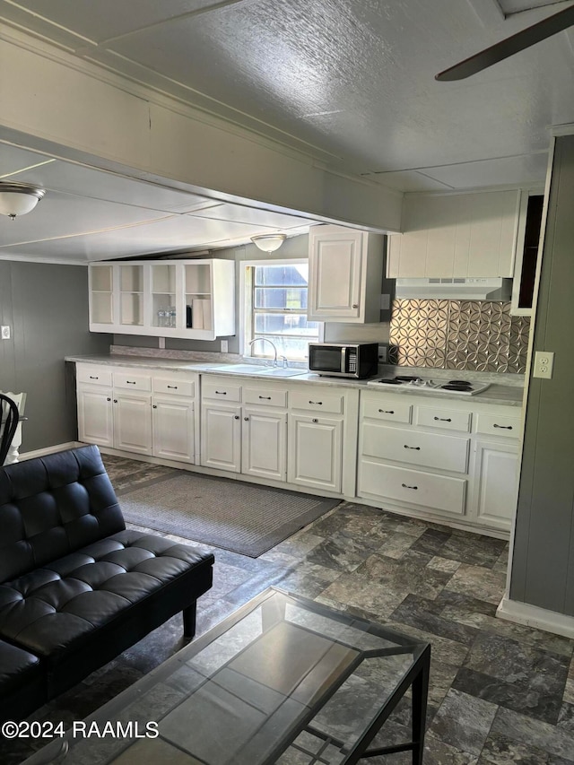 kitchen with white gas stovetop, sink, dark tile patterned flooring, decorative backsplash, and white cabinetry