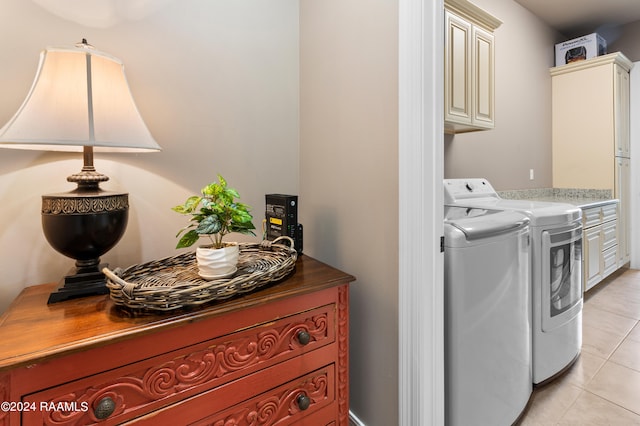 clothes washing area featuring cabinets, light tile flooring, and washing machine and clothes dryer