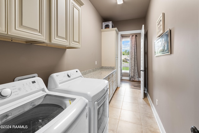 laundry room featuring washing machine and clothes dryer, cabinets, and light tile floors