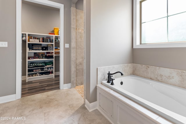 bathroom featuring a bath to relax in and tile flooring