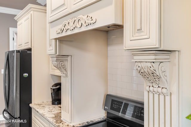 kitchen featuring black fridge, stove, light stone countertops, and ornamental molding