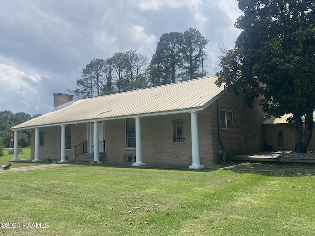 ranch-style home with a front yard, brick siding, metal roof, and a chimney