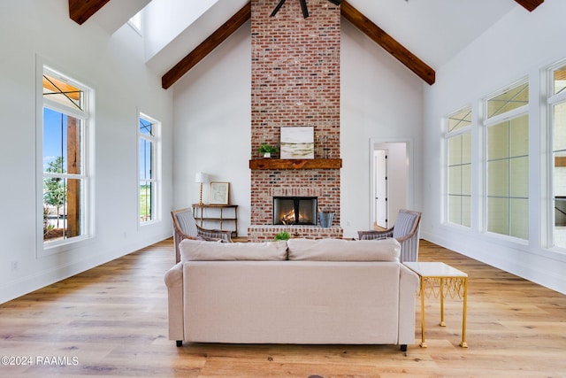 living room featuring beamed ceiling, a fireplace, brick wall, and hardwood / wood-style floors