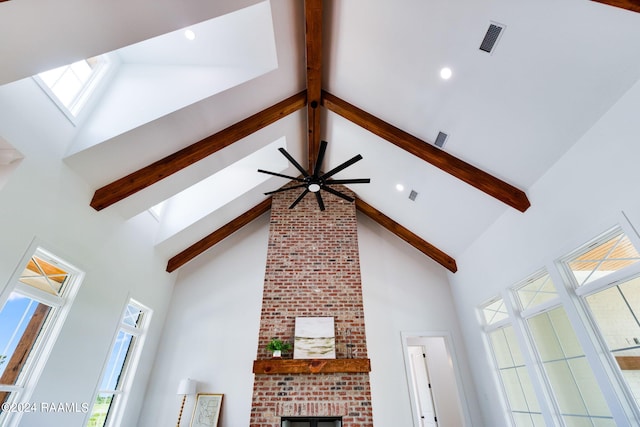 room details featuring ceiling fan, beam ceiling, and a fireplace