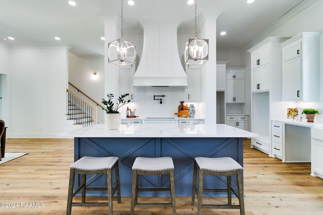 kitchen featuring decorative light fixtures, light hardwood / wood-style floors, tasteful backsplash, white cabinetry, and premium range hood