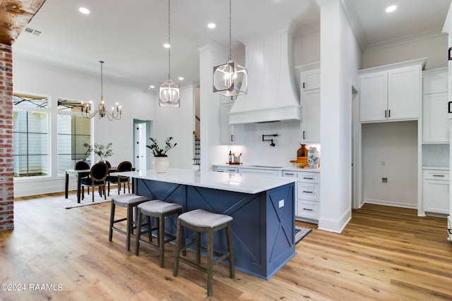 kitchen featuring backsplash, custom exhaust hood, light hardwood / wood-style flooring, and white cabinets