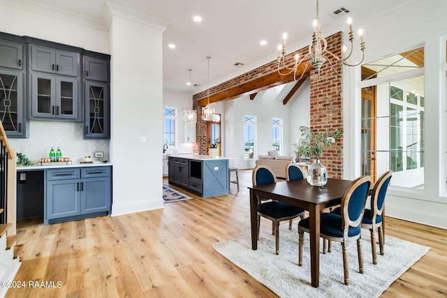 dining space with beamed ceiling, an inviting chandelier, brick wall, and light hardwood / wood-style flooring