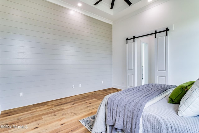 bedroom with ceiling fan, hardwood / wood-style flooring, a barn door, beam ceiling, and a high ceiling