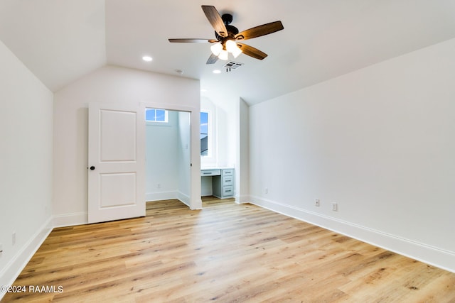 interior space with ceiling fan, vaulted ceiling, connected bathroom, and light wood-type flooring