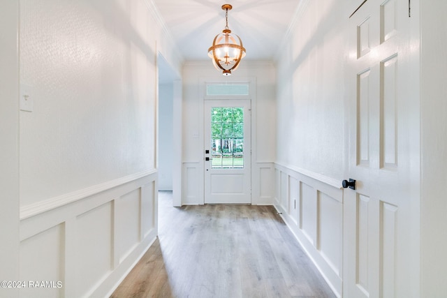 doorway featuring crown molding, an inviting chandelier, and light hardwood / wood-style floors